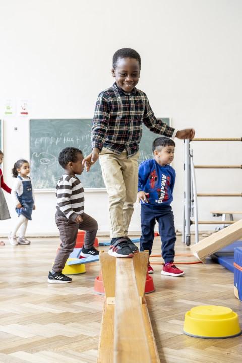 Kinderen balanceren op een balk in een turnles van stedelijke basisschool Het Atelier